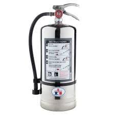 Portable fire extinguisher with a black hose and instructional label, standing on a metal base.